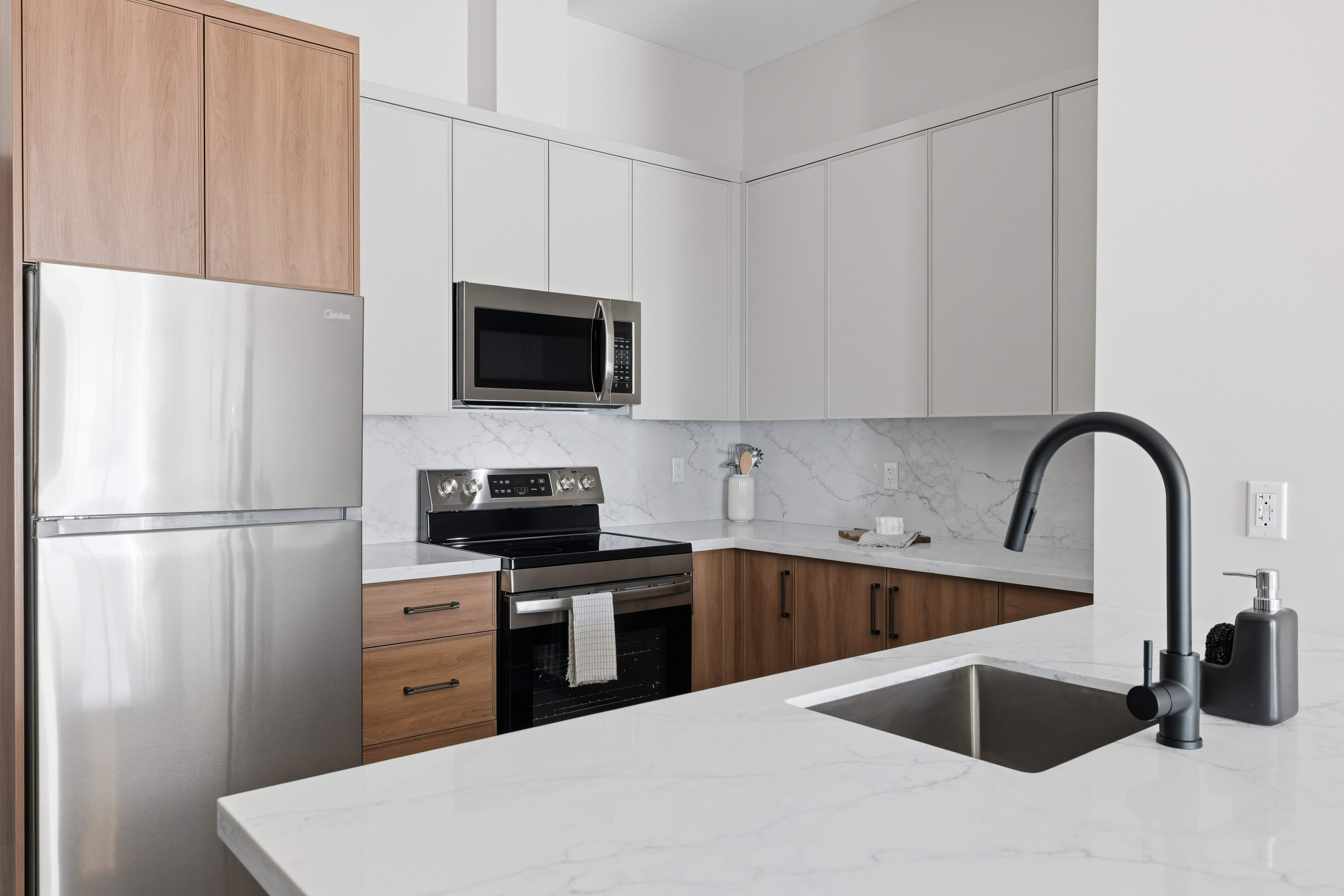 Santé Apartments — Designer kitchen with stainless appliances and quartz countertops